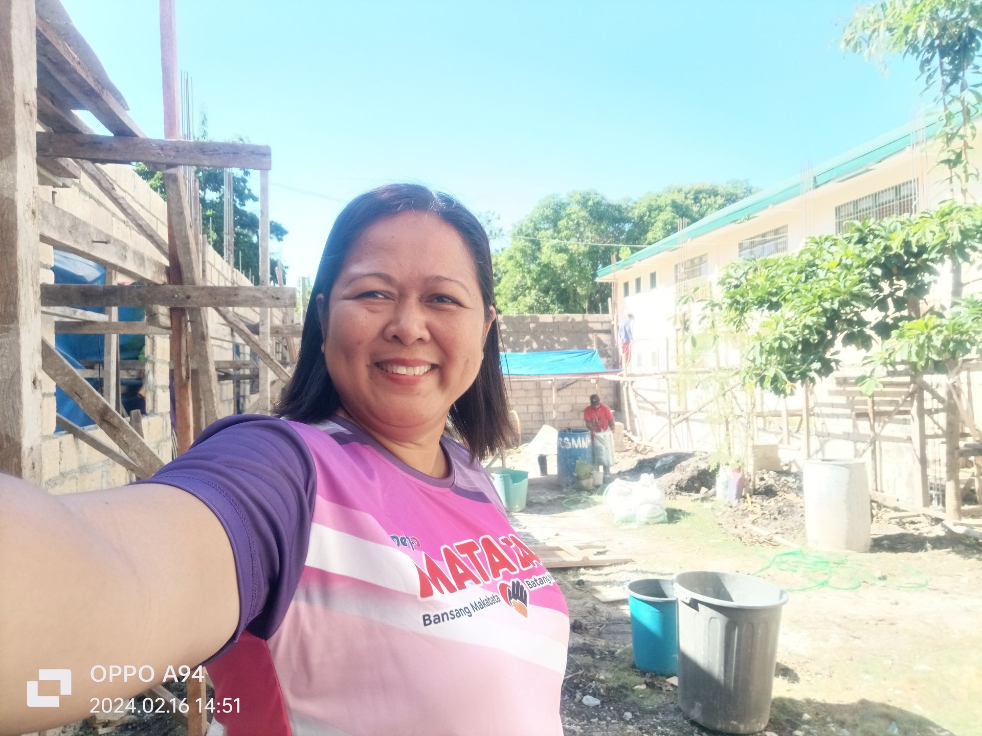 A woman is taking a selfie in front of a building under construction.