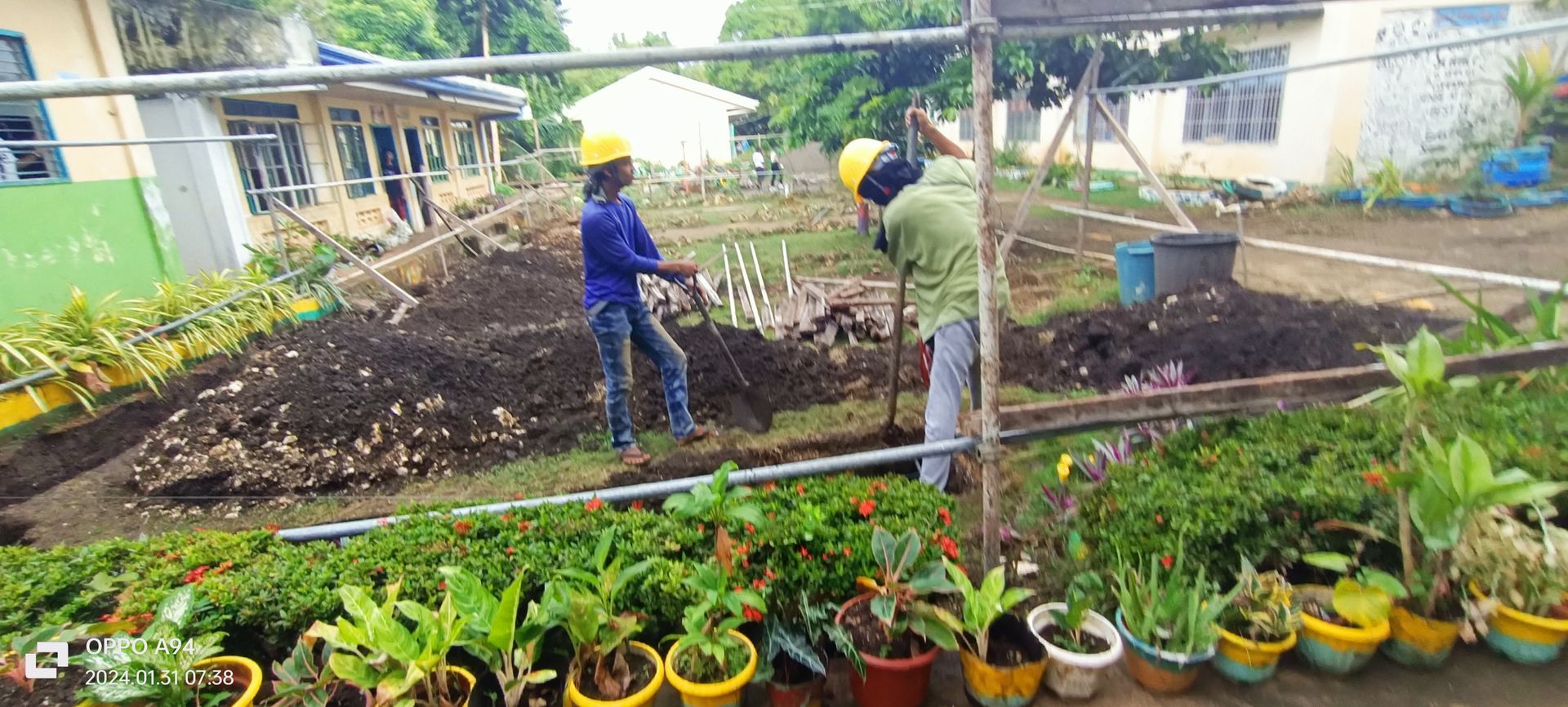 Two men are working in a garden with potted plants.