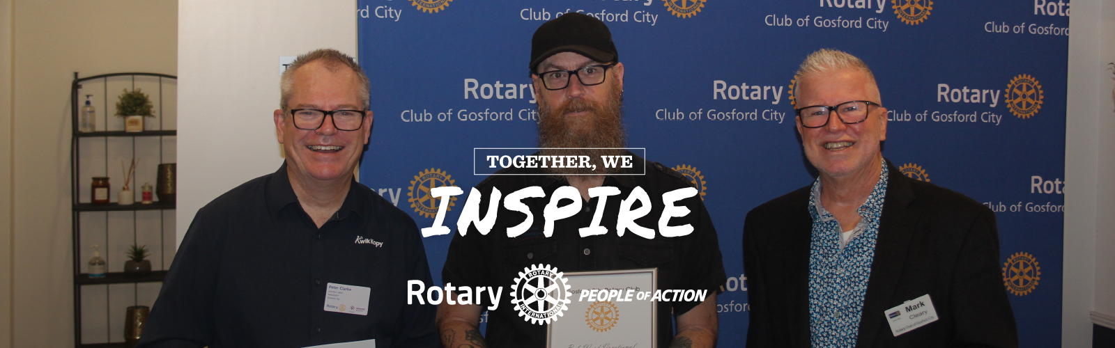 Three men are standing next to each other in front of a sign that says inspire.