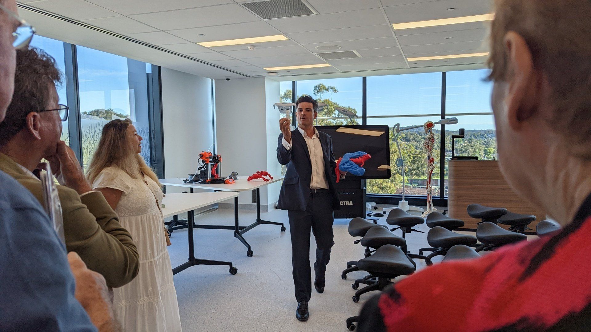A man in a suit is giving a presentation to a group of people in a room.