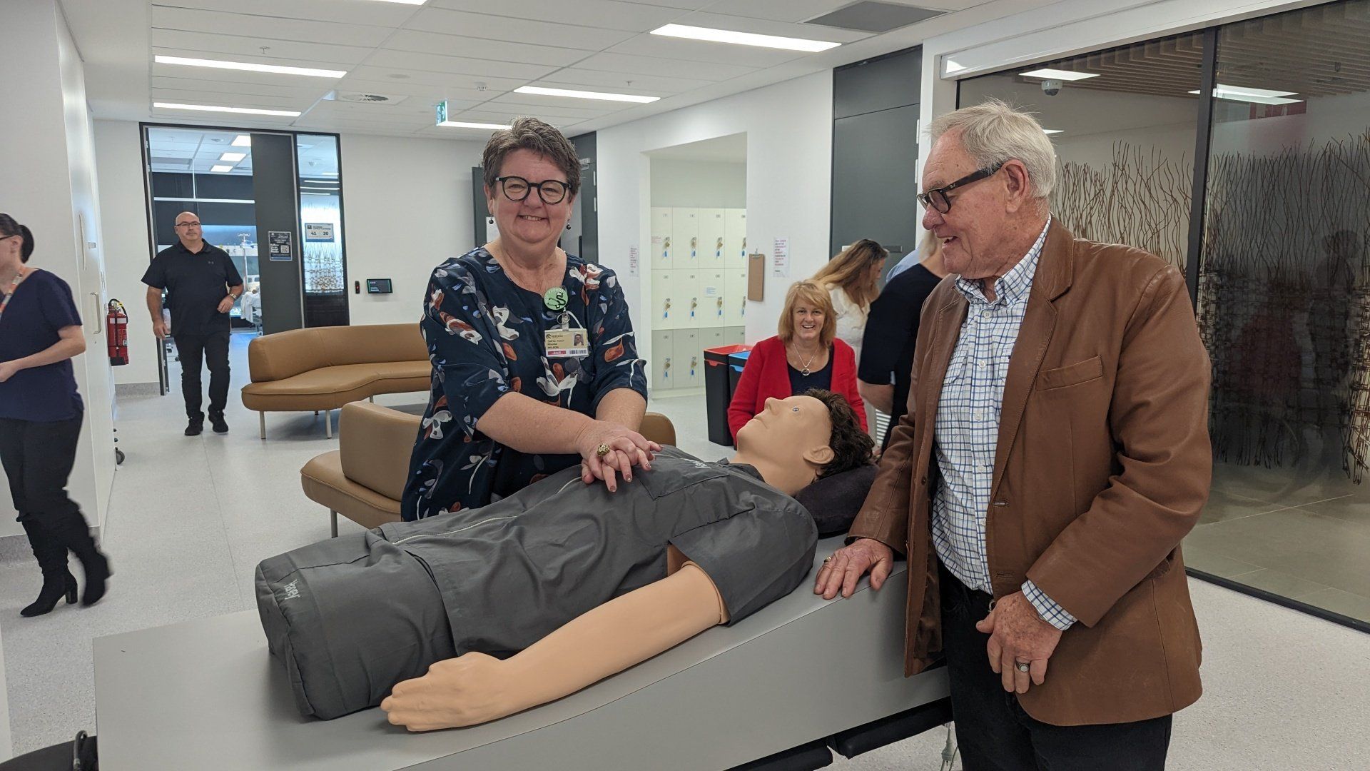 A man and a woman are standing next to a mannequin in a hospital.