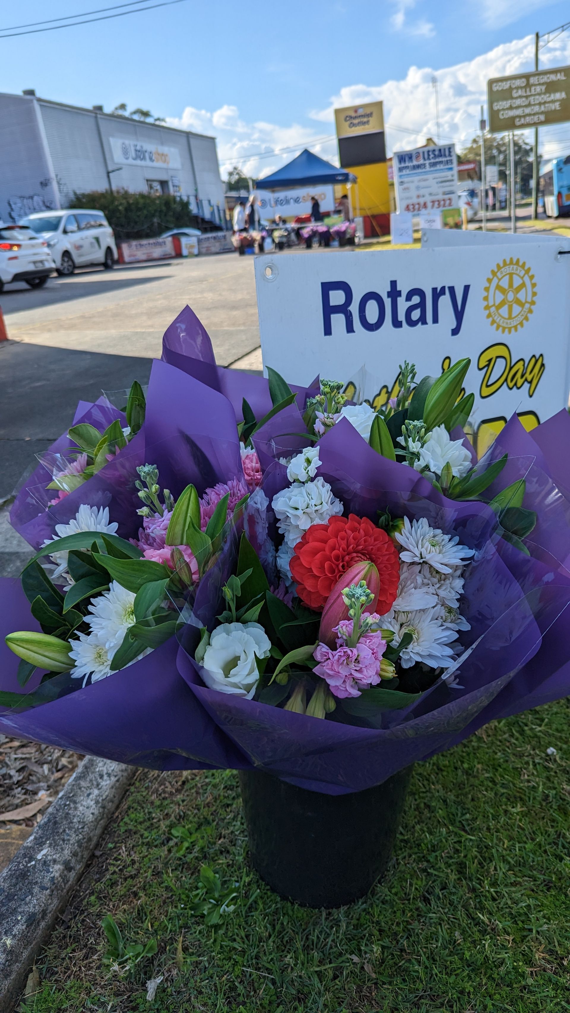 A bouquet of flowers is sitting in front of a rotary sign.
