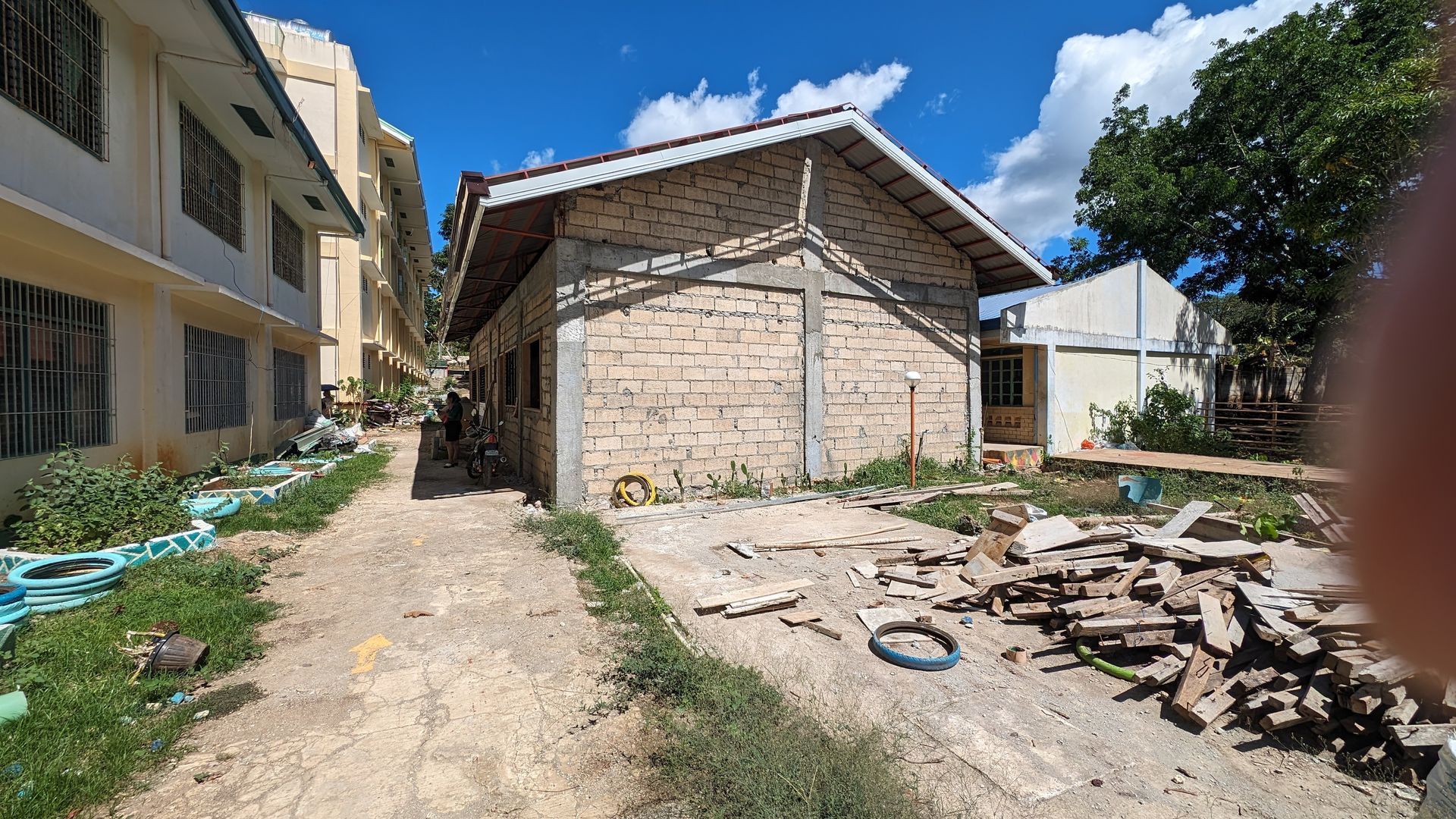 A dirt road leading to a brick building with a roof.