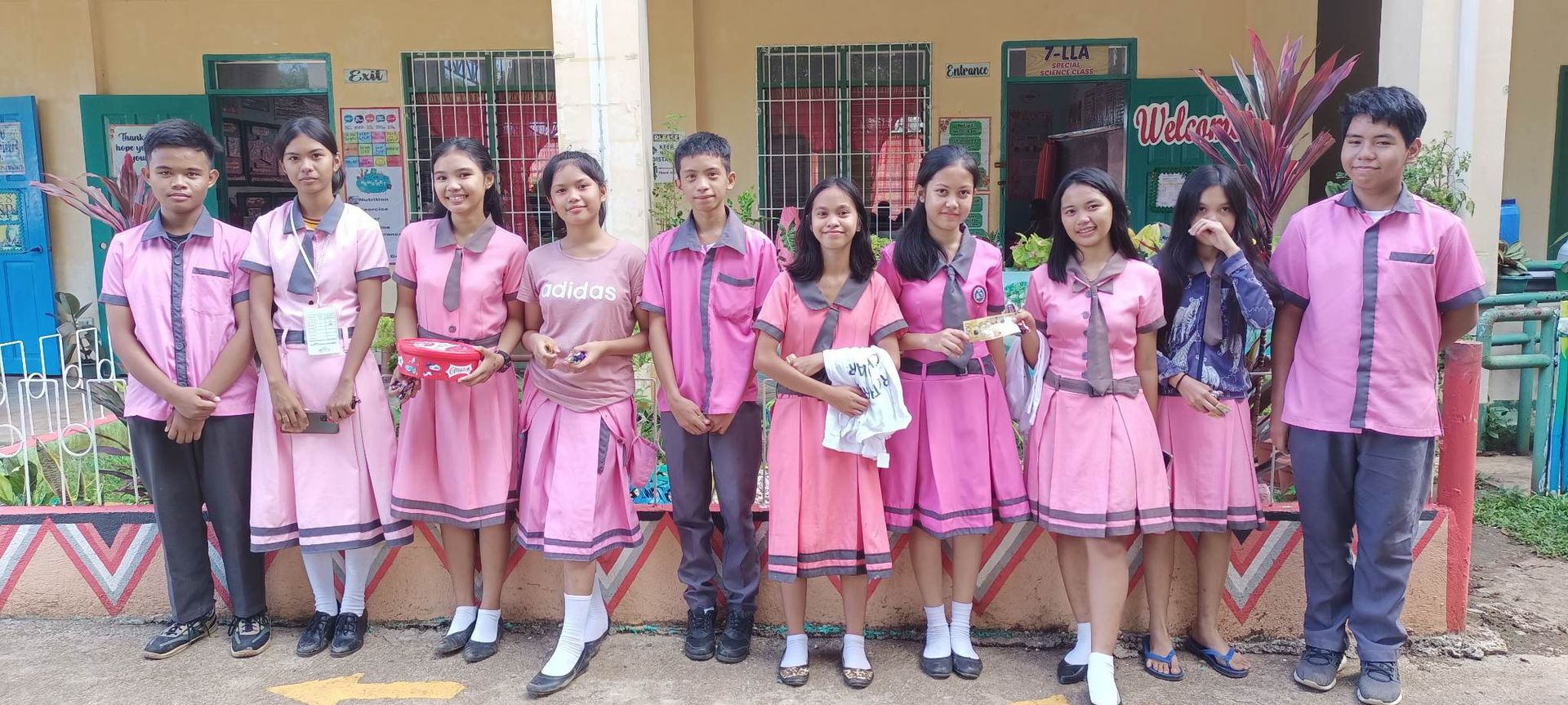 A group of young people in pink uniforms are posing for a picture.