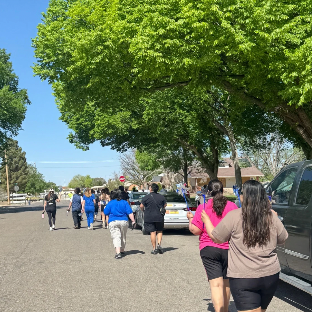People walking down a tree-lined suburban street on a sunny day