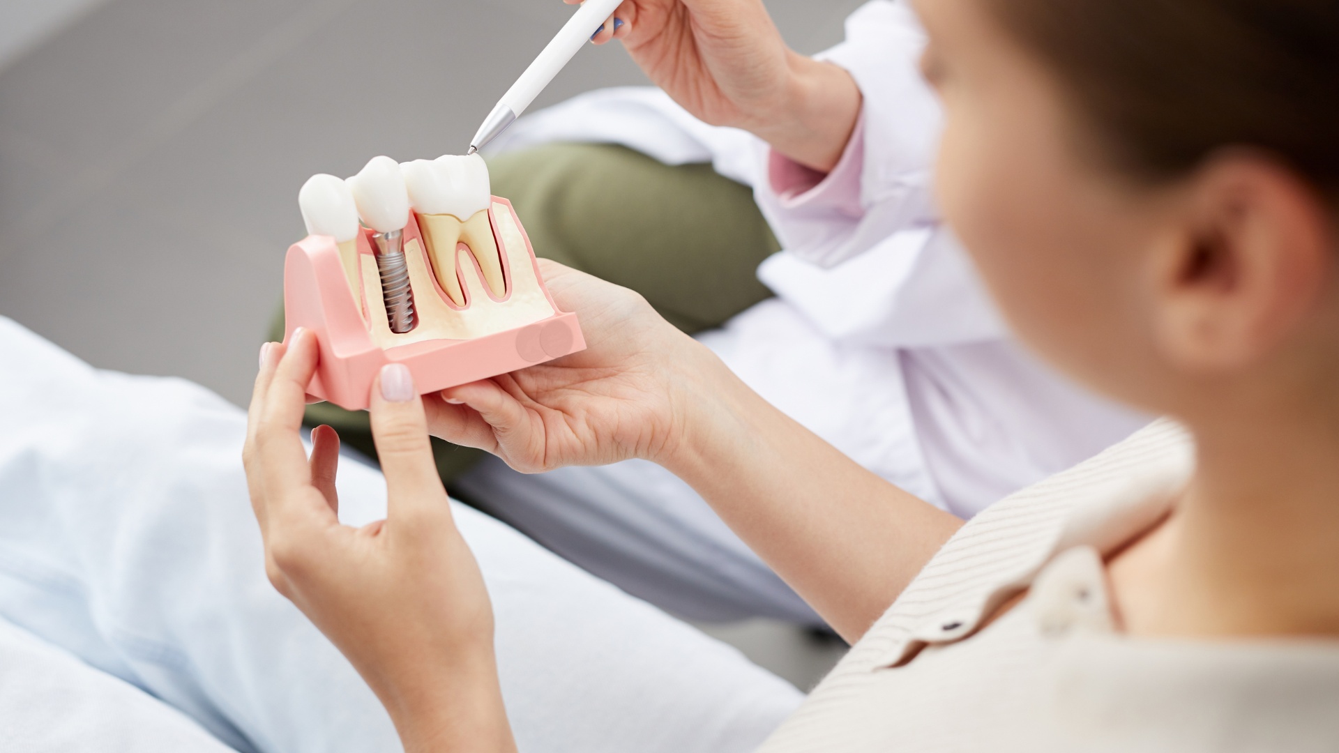 A woman is holding a model of dental implants in her hands.