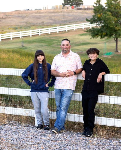 Three people standing by a white fence on a rural hillside path.
