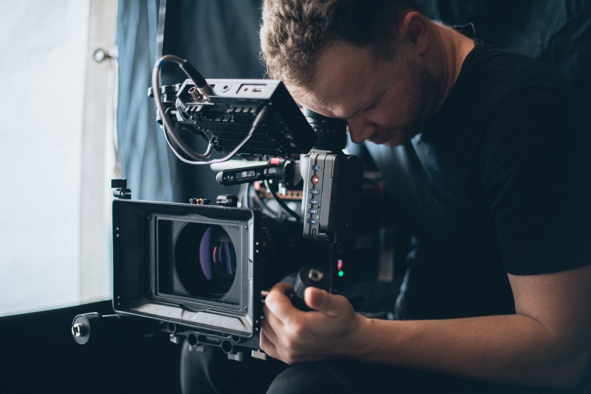 Cameraman adjusting a professional video camera in a dimly lit studio setup