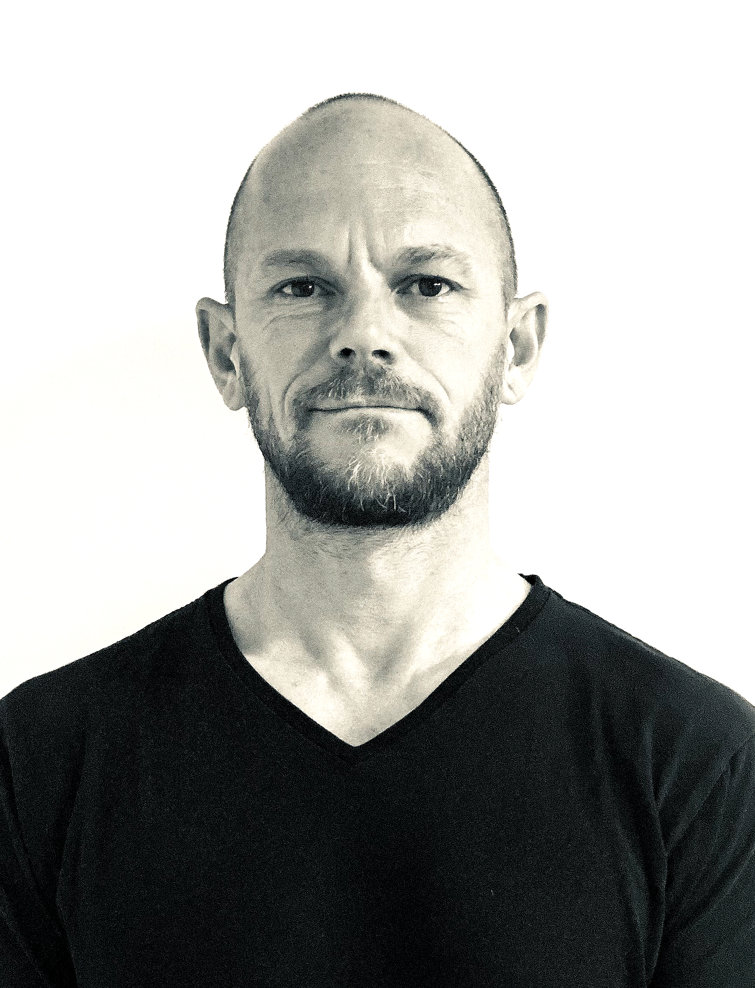 Portrait of a bald man with a beard wearing a black V-neck shirt against a white background