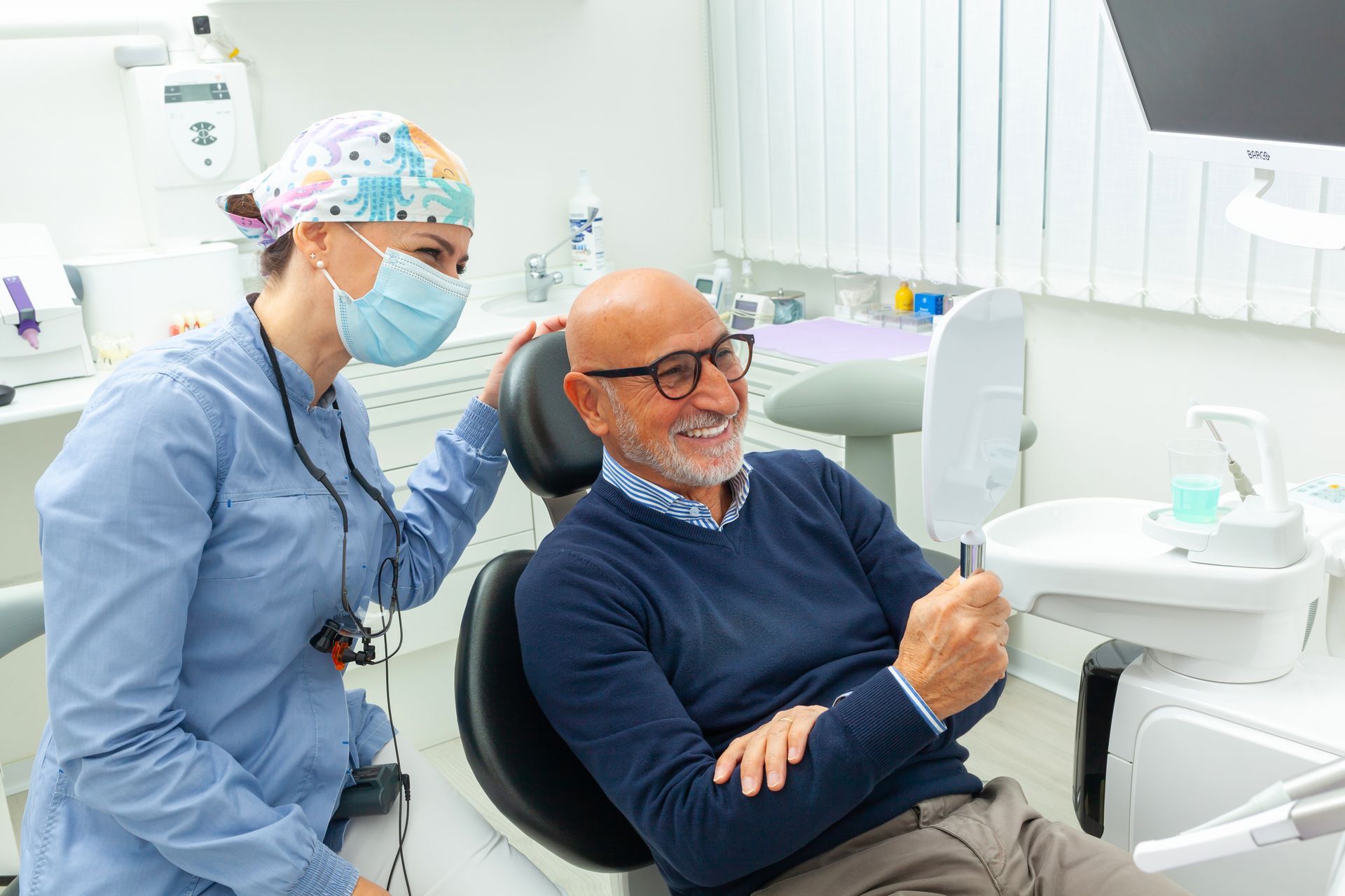 Dentist showing a smiling patient their teeth in a dental office.