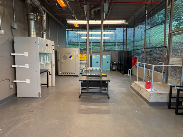 Industrial lab room with large machinery, a central table, and a raised platform under high ceilings