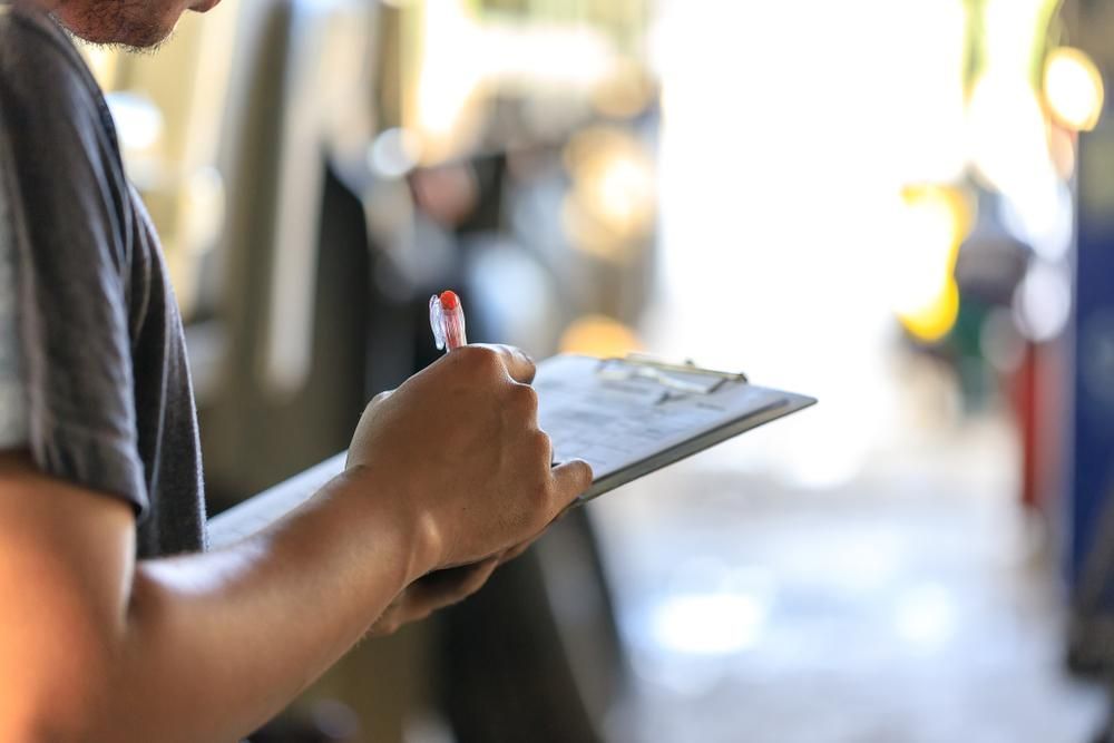 A Man Is Holding A Clipboard And Writing On It — Active Ables Community Services In Logan, QLD