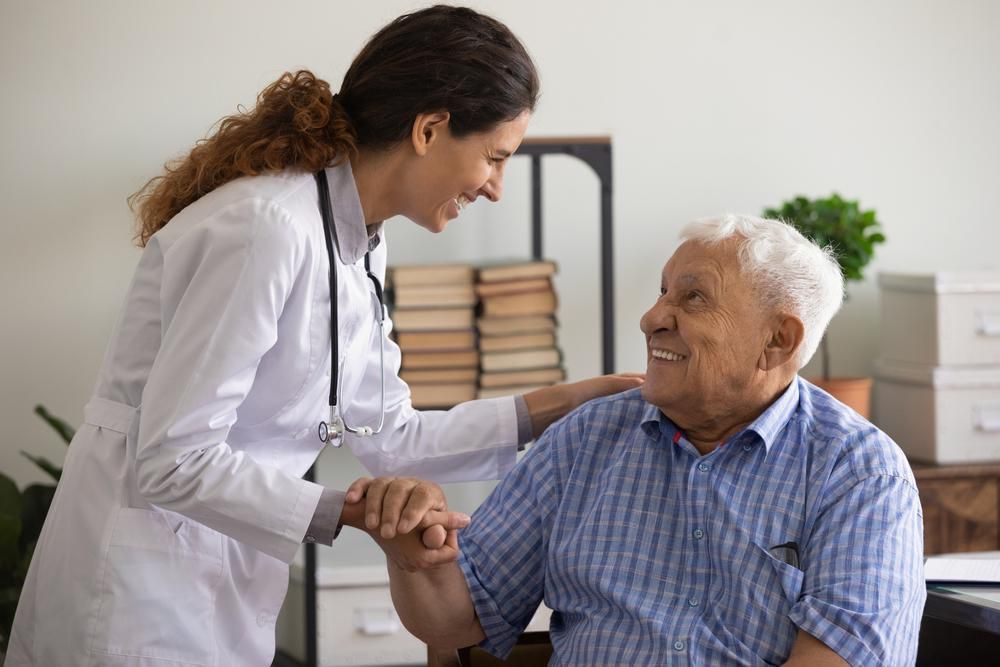 A Doctor Is Holding The Hand Of An Elderly Man In A Wheelchair — Active Ables Community Services In Tamworth, NSW