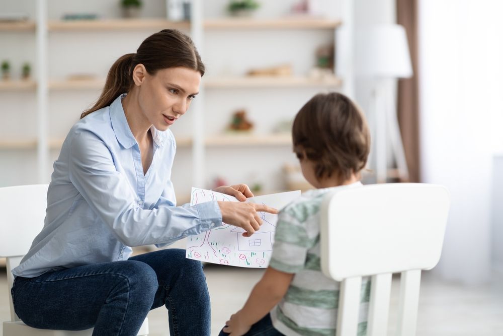 Teacher Helping a Child with A Worksheet in A Bright Classroom — Active Ables Community Services In Brookwater, QLD