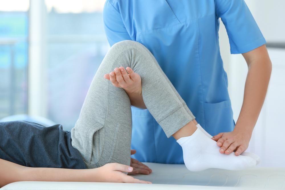 A Nurse Is Stretching A Patient 's Leg On A Table — Active Ables Community Services In Tamworth, NSW