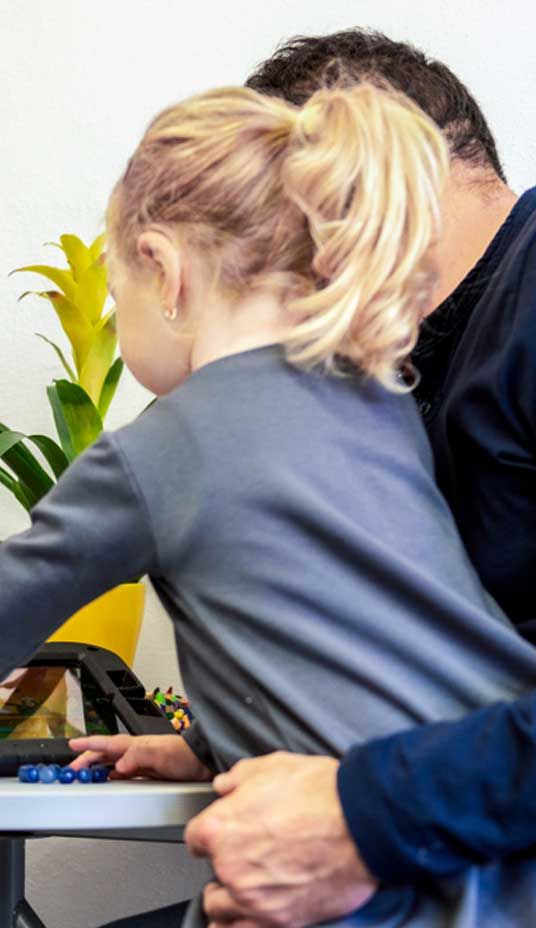 A Man Is Hugging a Little Girl Who Is Sitting at A Table — Active Ables Community Services In Tamworth, NSW