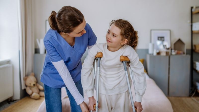 A Nurse Is Helping a Little Girl with Crutches — Active Ables Community Services In Tamworth, NSW