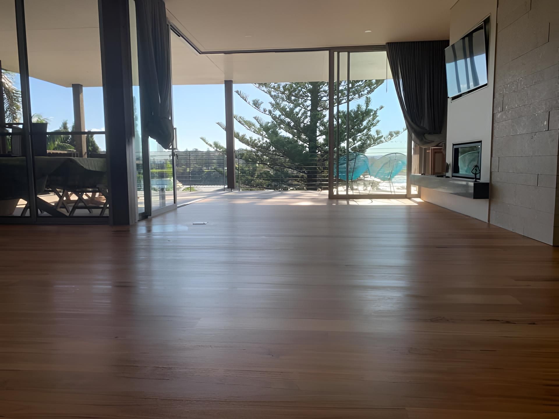 A living room with a wooden floor and a lot of windows โ Coolangatta Floor Sanding In Shoalhaven Heads, NSW
