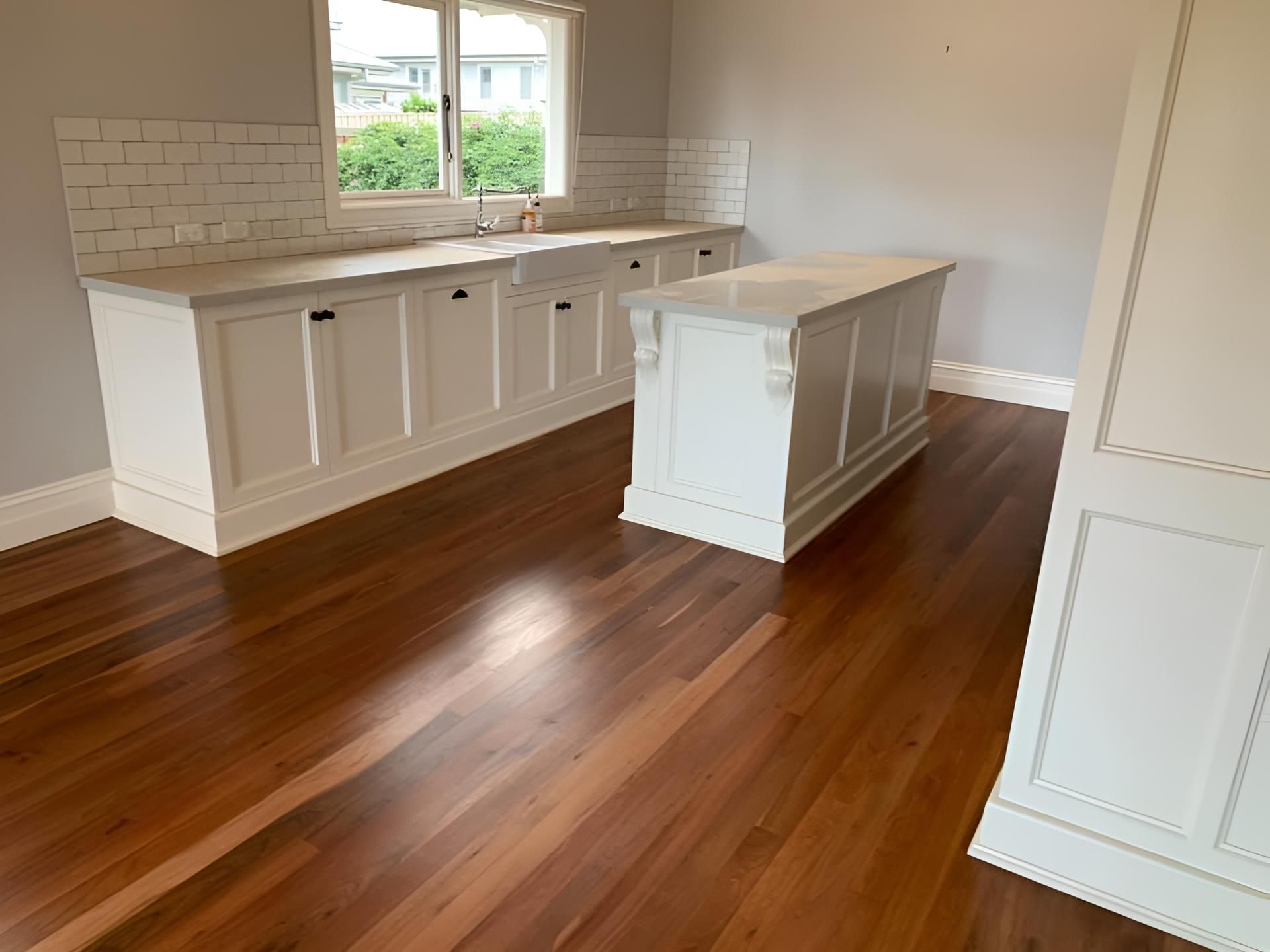 An empty kitchen with hardwood floors and white cabinets โ Coolangatta Floor Sanding In Shoalhaven Heads, NSW