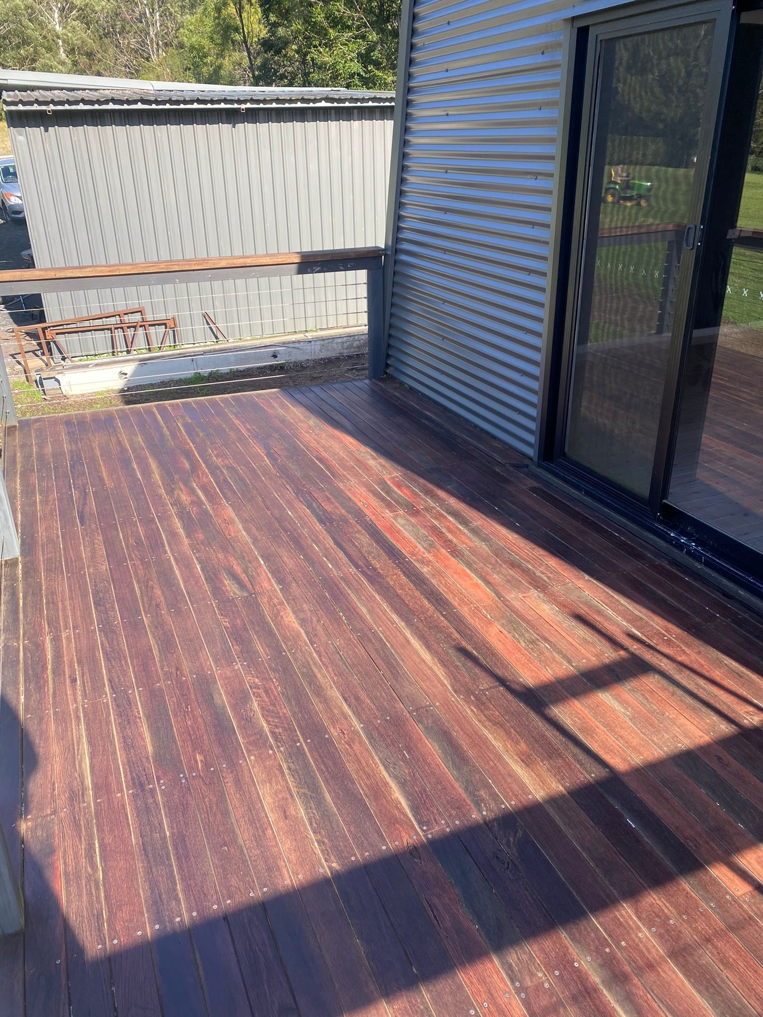 A wooden deck with a sliding glass door and a fence in the background โ Coolangatta Floor Sanding In Shoalhaven Heads, NSW