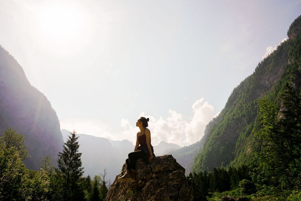 Silhouette of a person on a rock overlooking a sunlit mountain valley Silhouette of a person on a rock overlooking a sunlit mountain valley