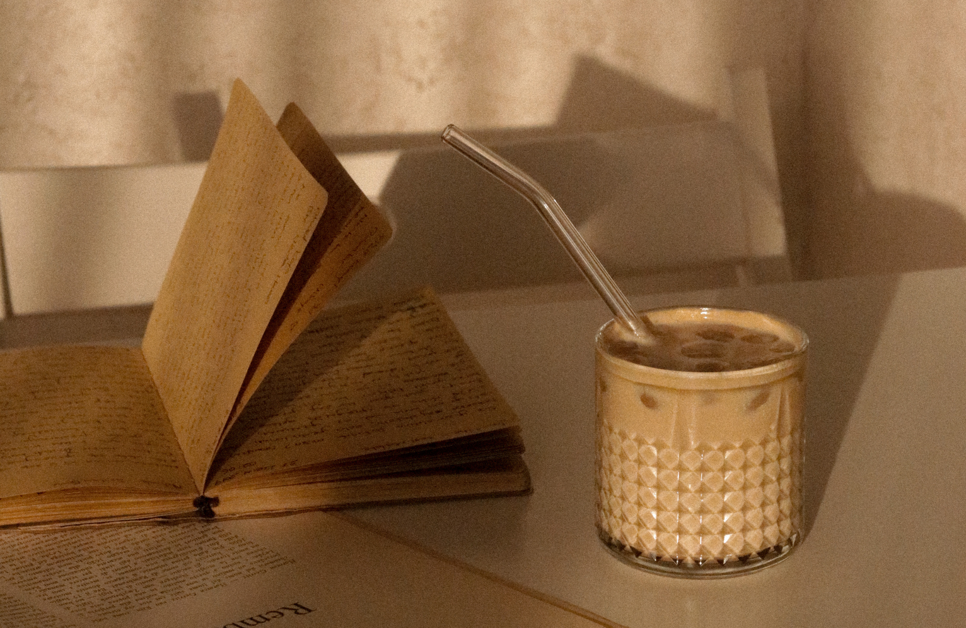 Open book on a table beside a woven cup holding a straw