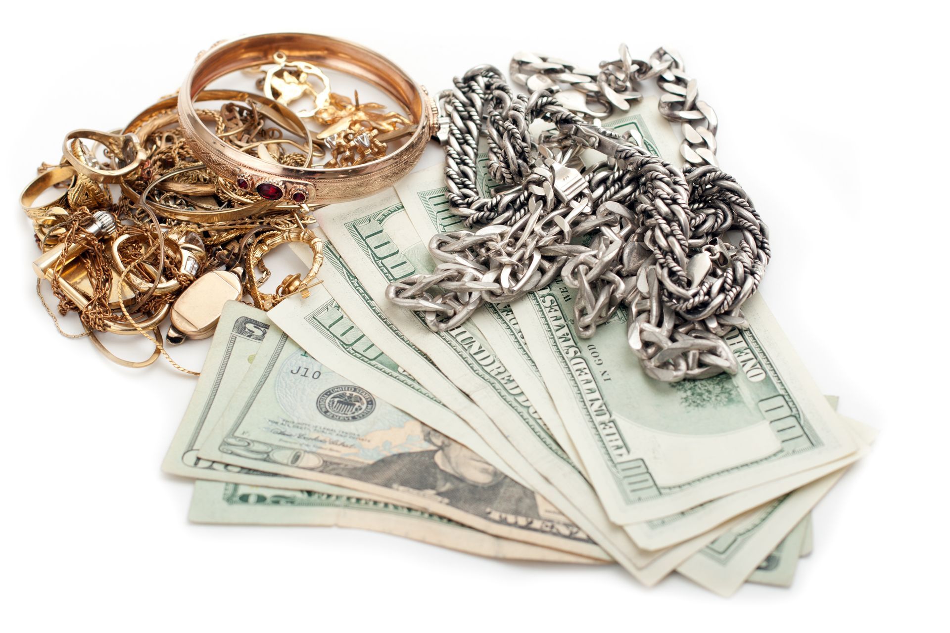 Gold jewelry and silver chains next to a fan of U.S. cash.