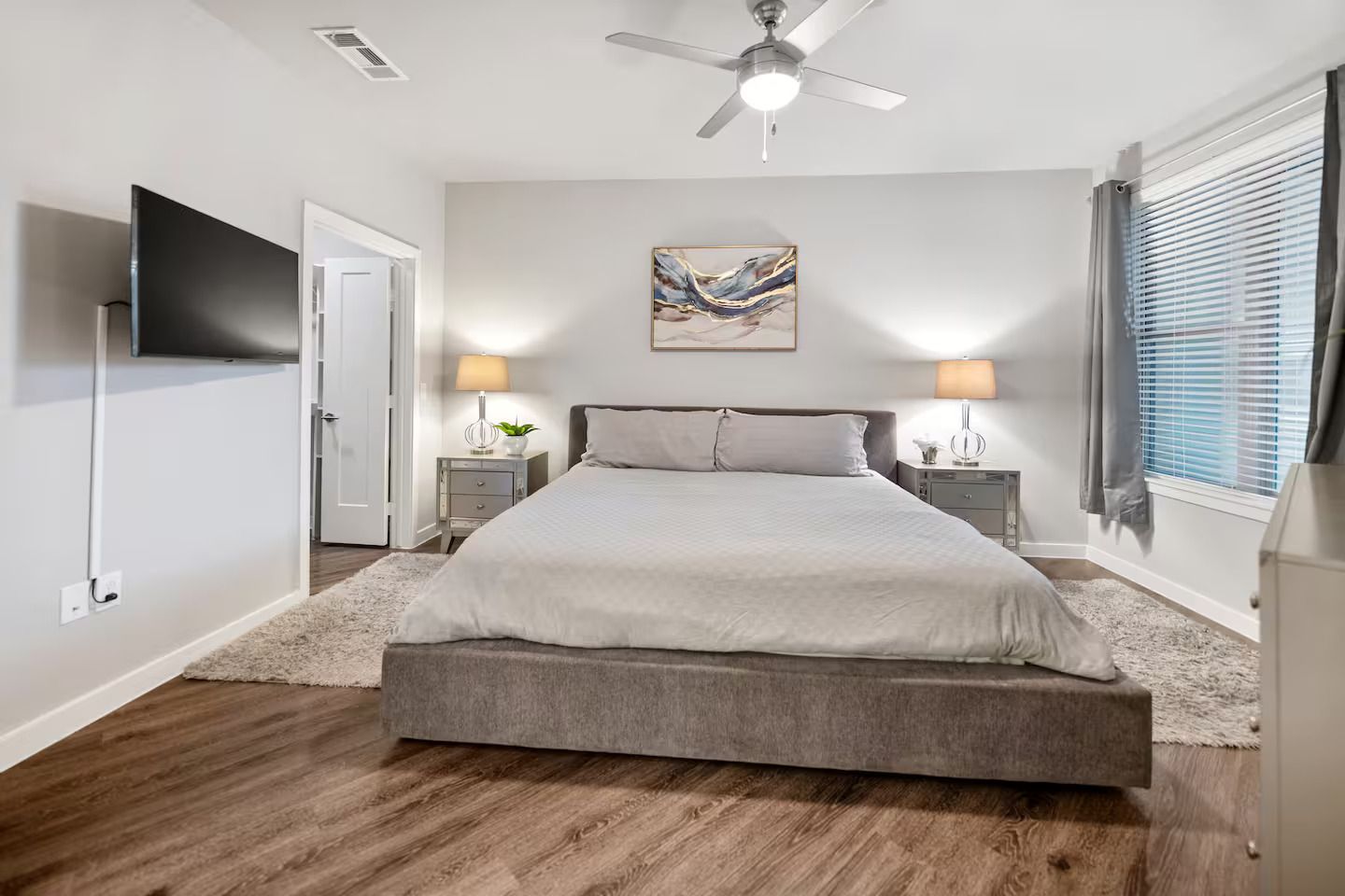 A bedroom with a king size bed and a flat screen tv on the wall.