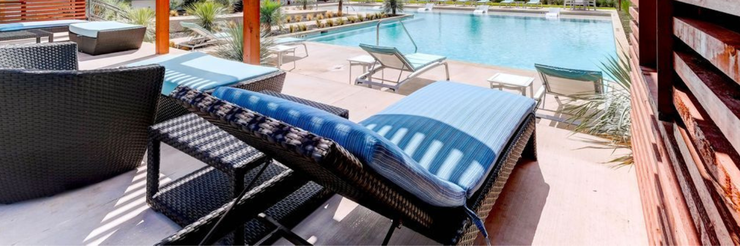 A patio with chairs and a swimming pool in the background.