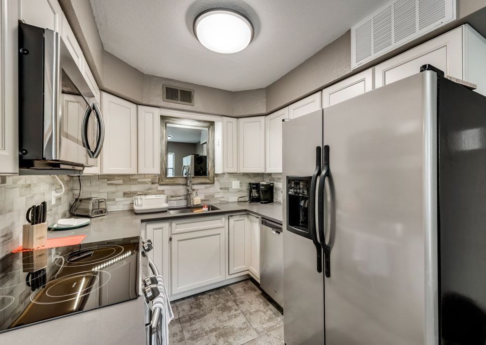 A kitchen with stainless steel appliances and white cabinets.