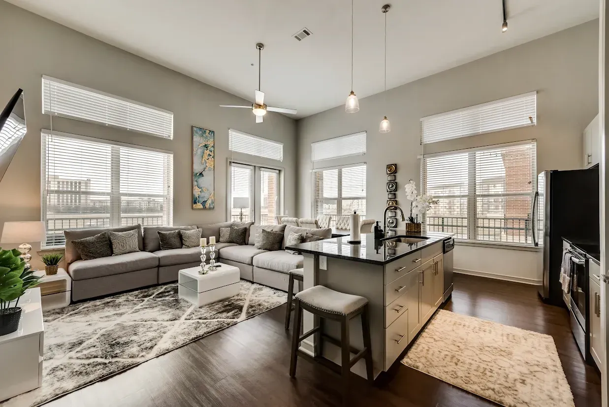 A living room with a couch and a kitchen with stainless steel appliances.