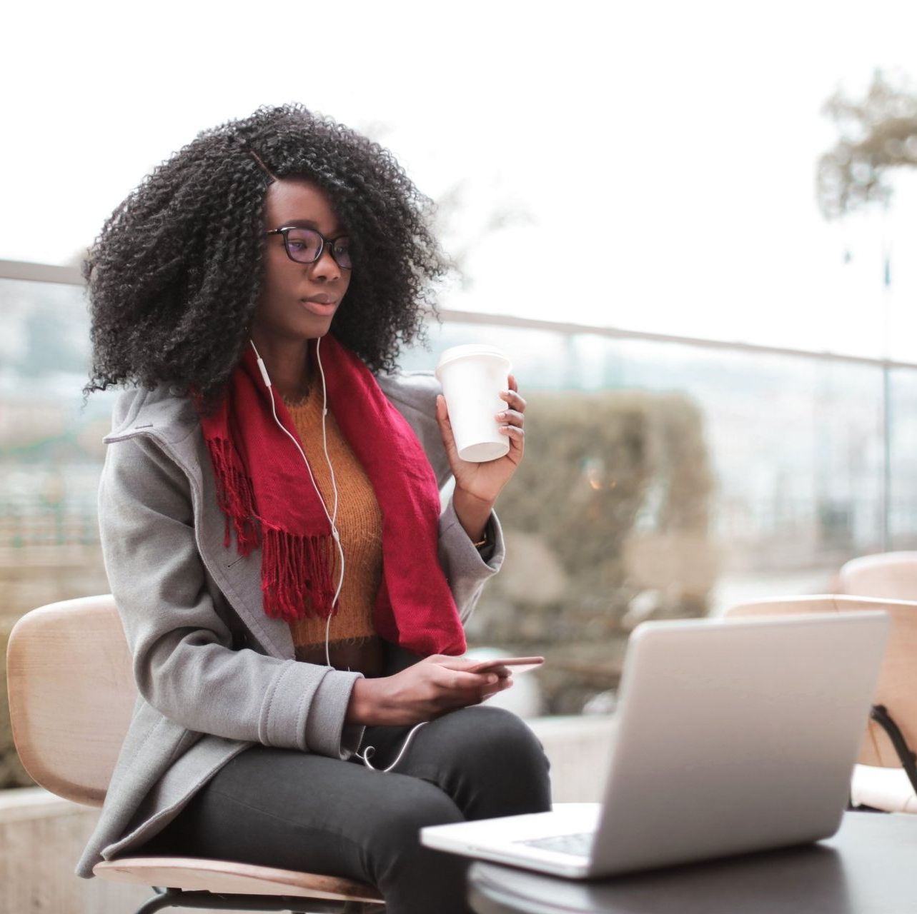 A woman is sitting at a table with a laptop and a cup of coffee.