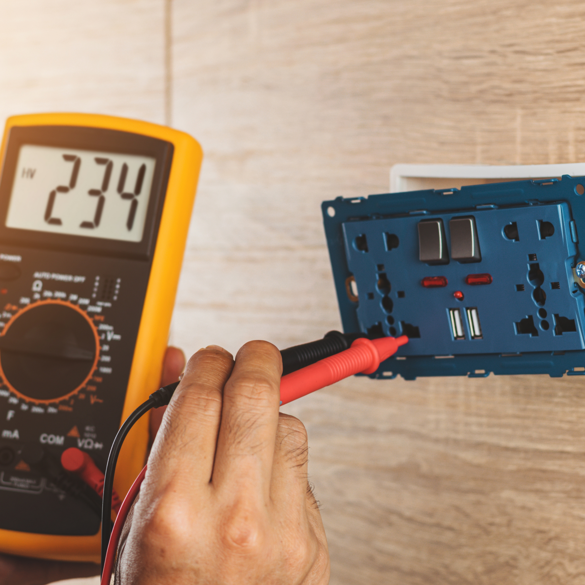 Electrician testing voltage at an electrical outlet with a multimeter, showing 234 volts on the display.