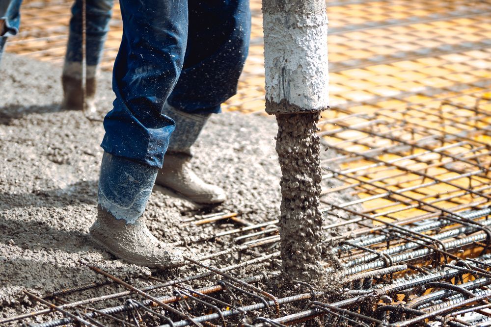 Construction worker pouring concrete over rebar at a building site
