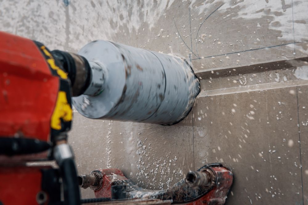 Core drilling through a concrete wall, with water spraying from the drill bit