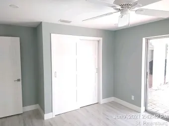 Bedroom with pale blue walls, white trim, sliding closet doors, and a door to outside.