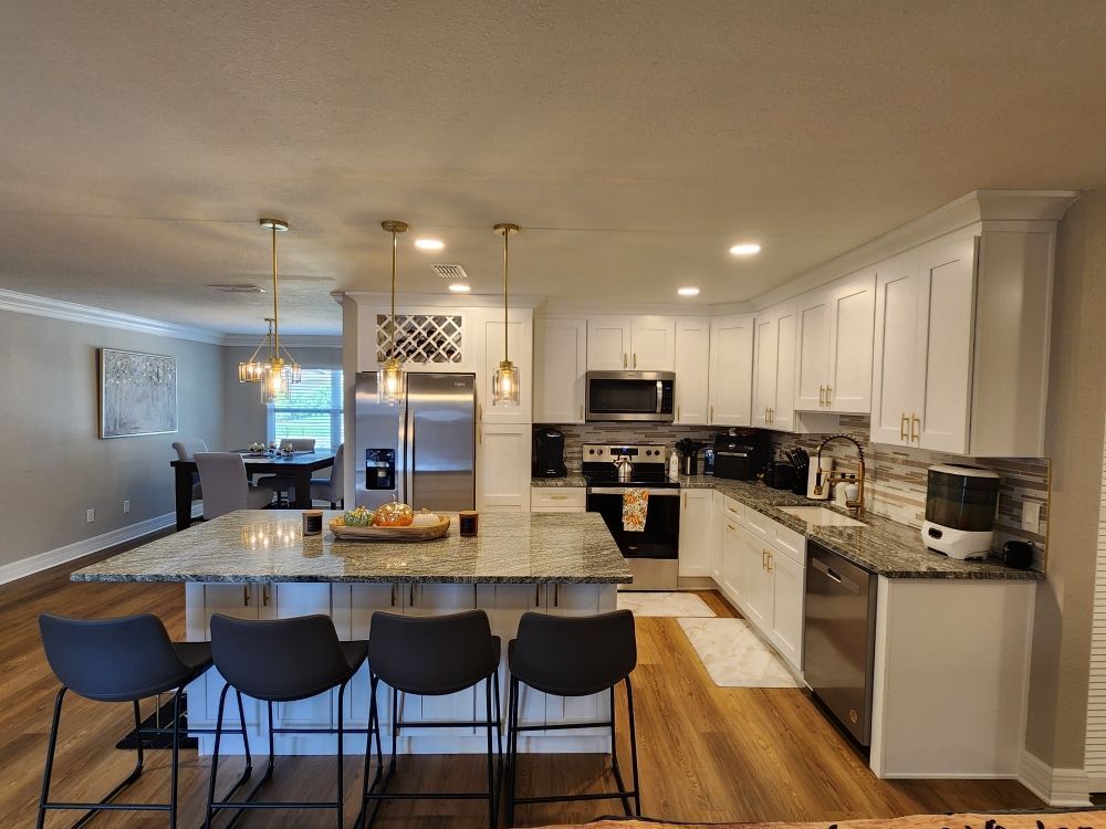 Modern kitchen with white cabinets, granite countertops, and a large island with bar stools.