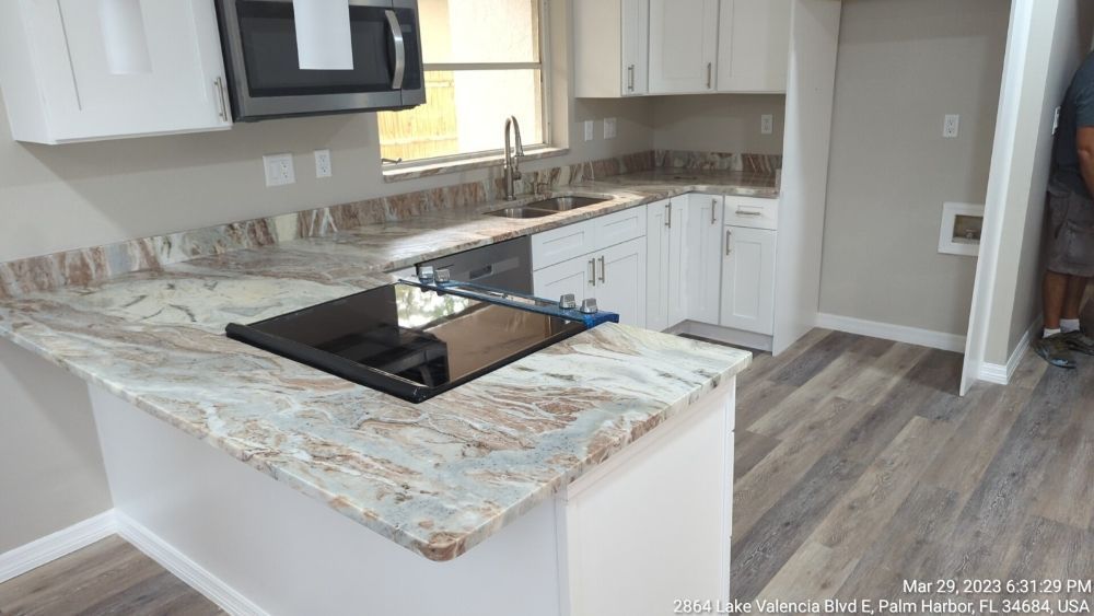 Modern kitchen with white cabinets, granite countertops, and wood-look flooring.