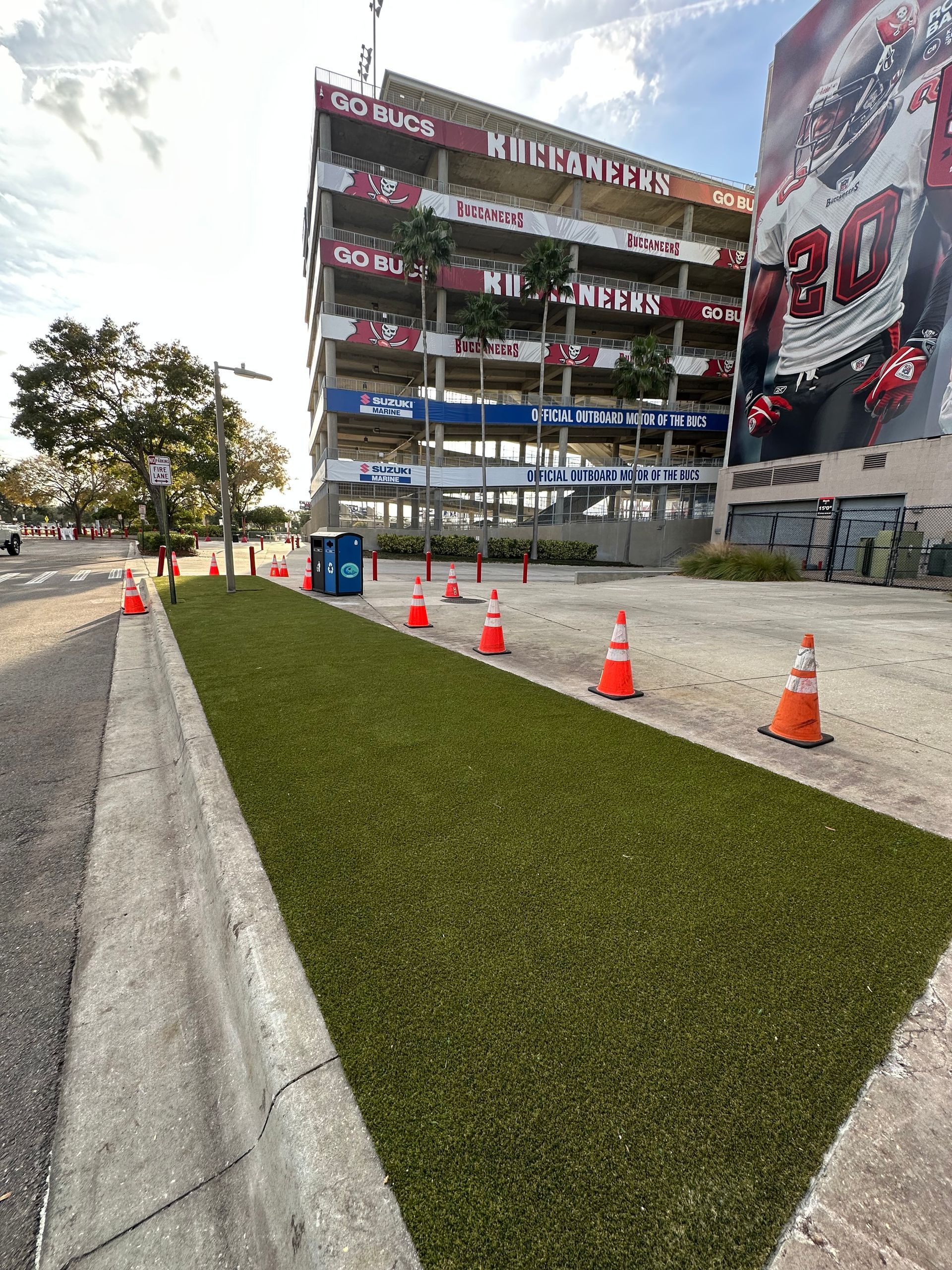 Person in gloves rolling out artificial turf on a dark surface.