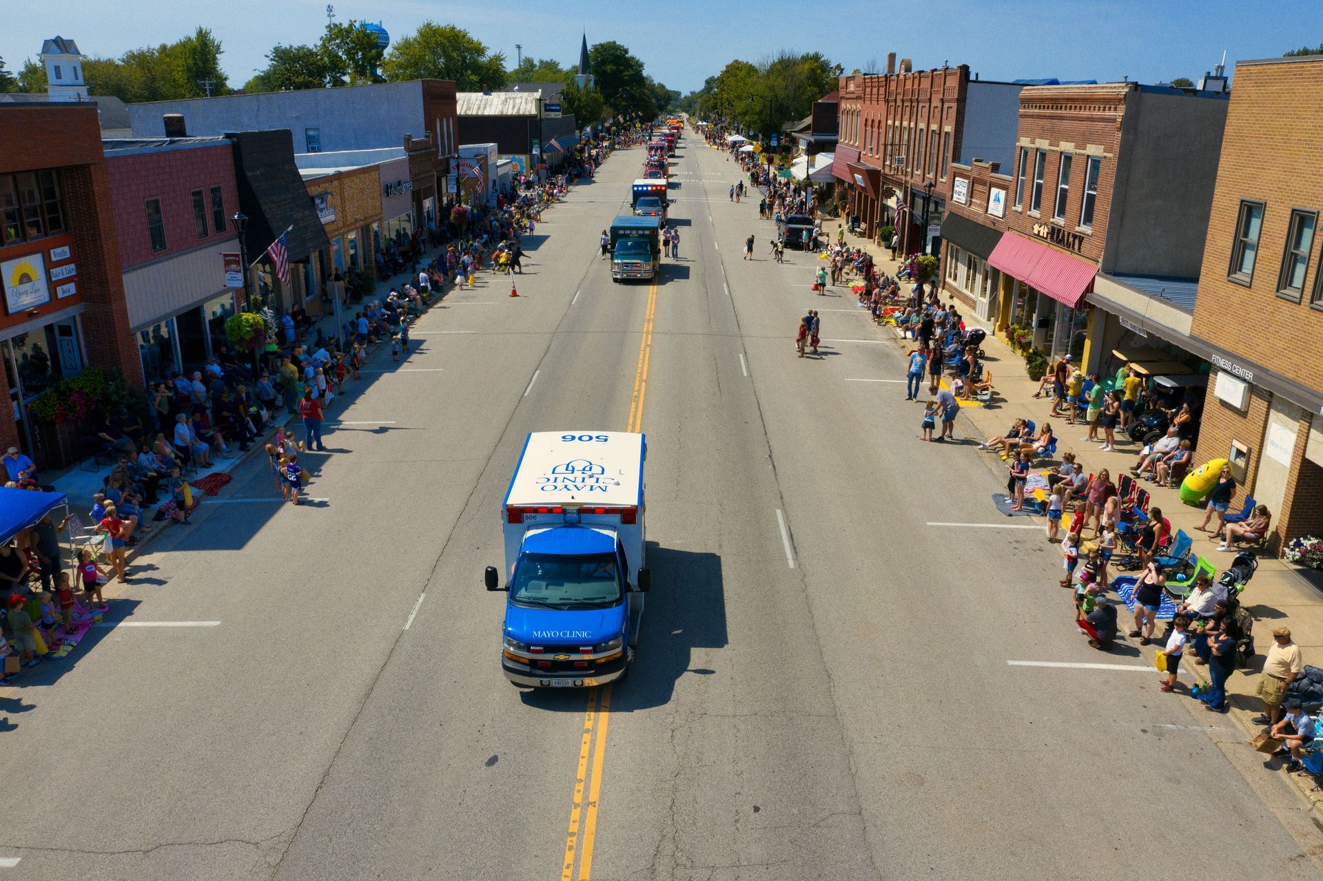 Parade float truck on a small-town main street lined with spectators and storefronts