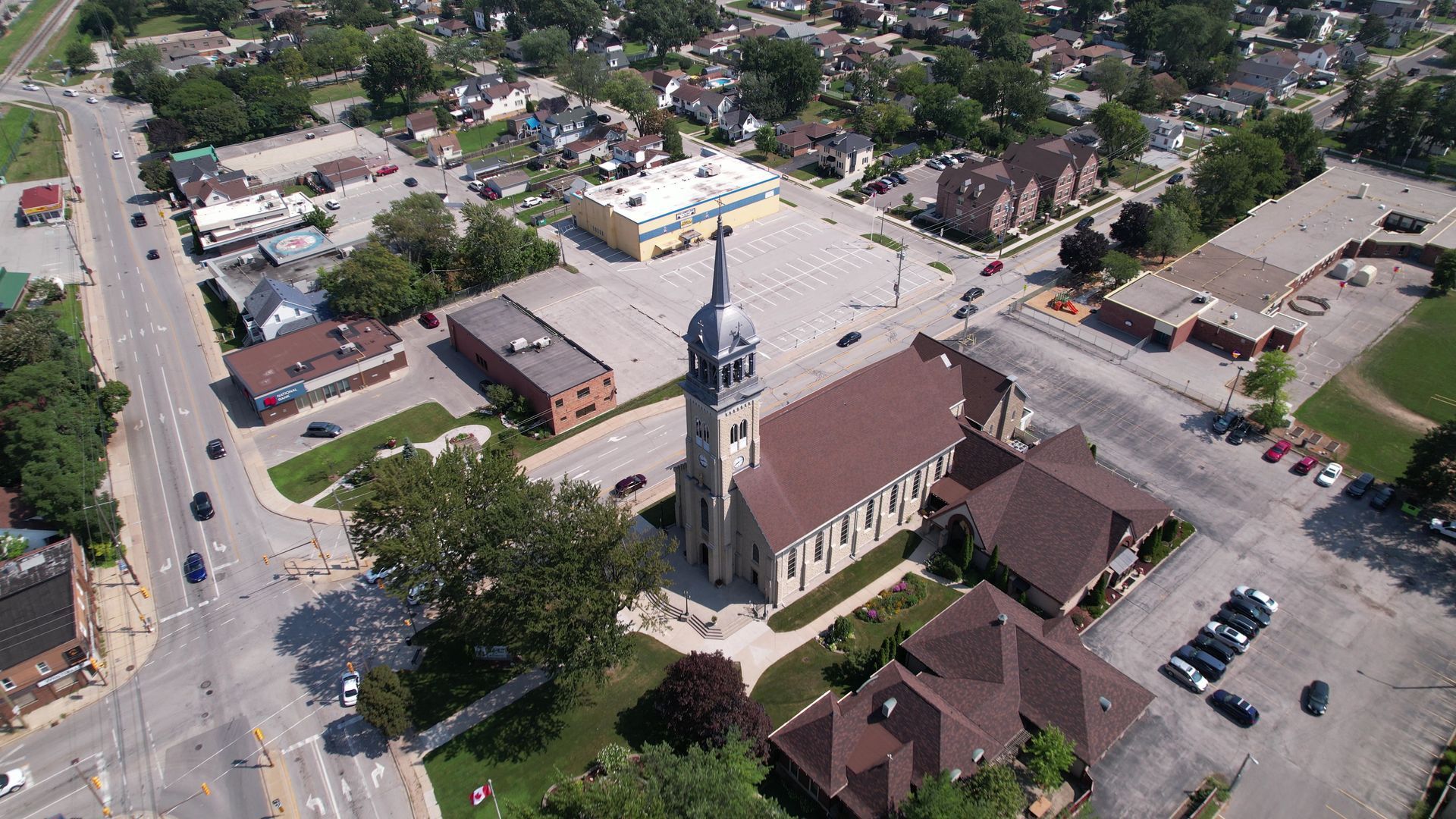 Aerial view of a church with a tall steeple in a small town, surrounded by streets and buildings.