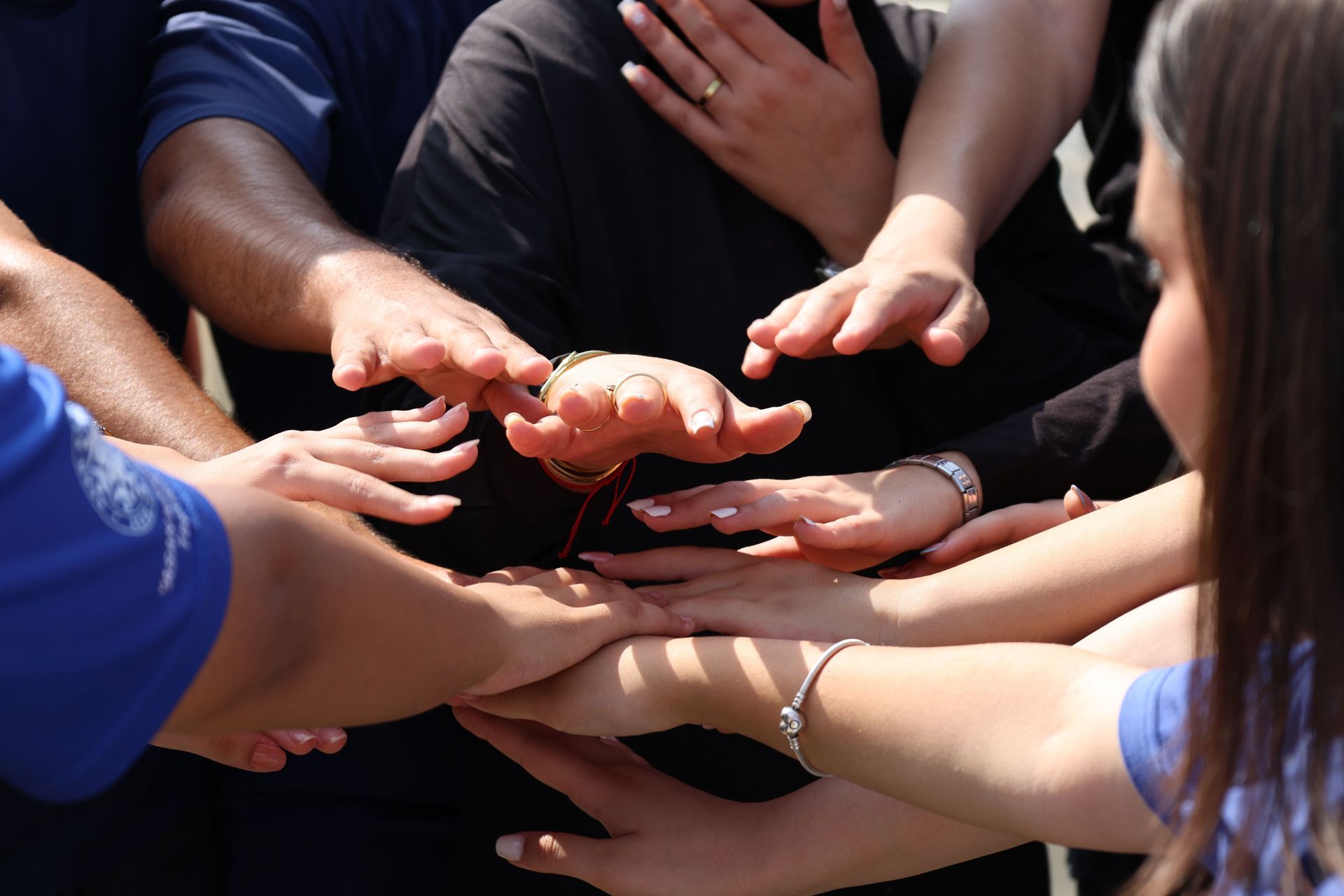 Hands stacked together in a group huddle, showing teamwork and support