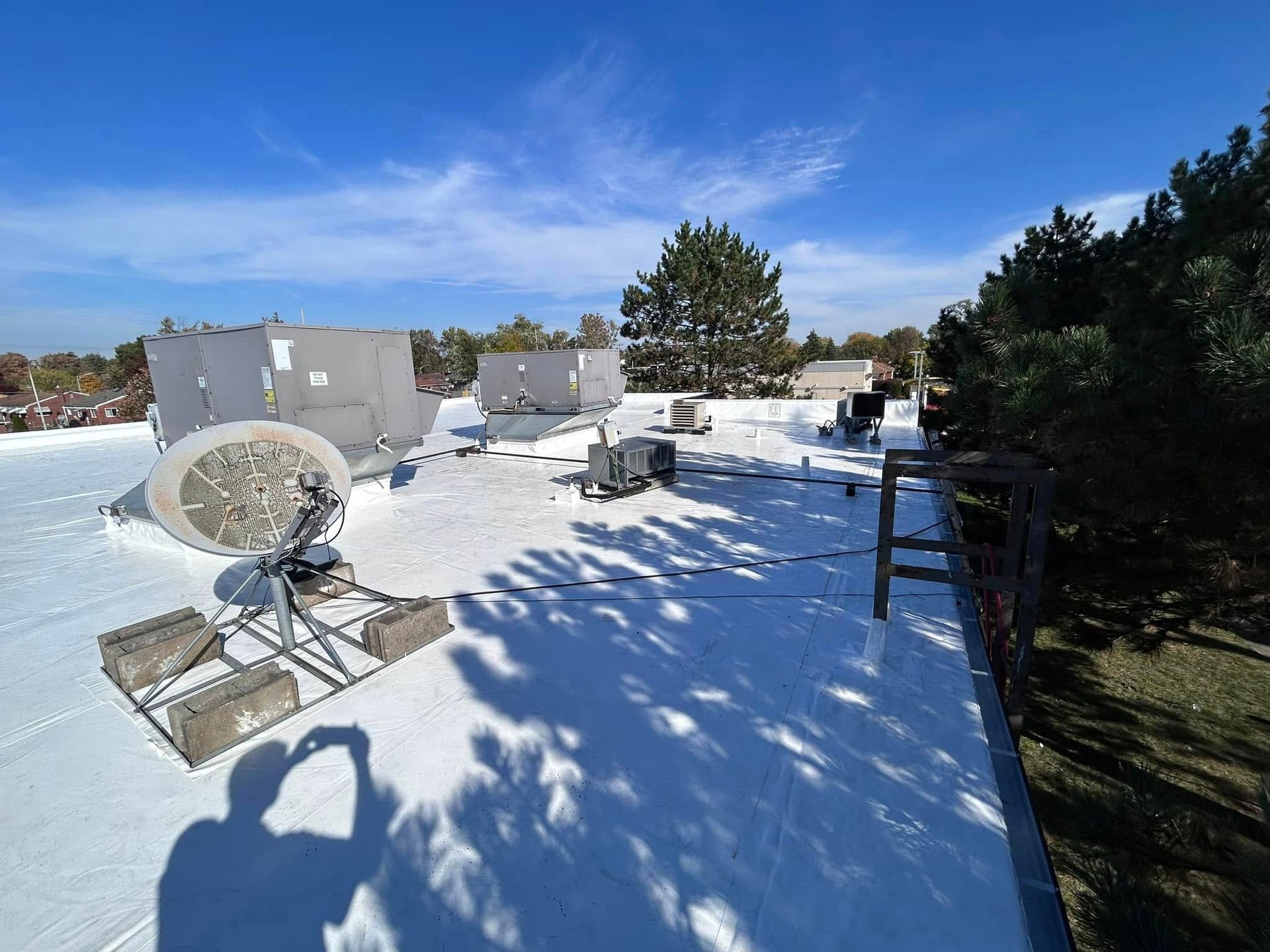 Snow-covered rooftop with satellite dish, HVAC units, and a blue sky.
