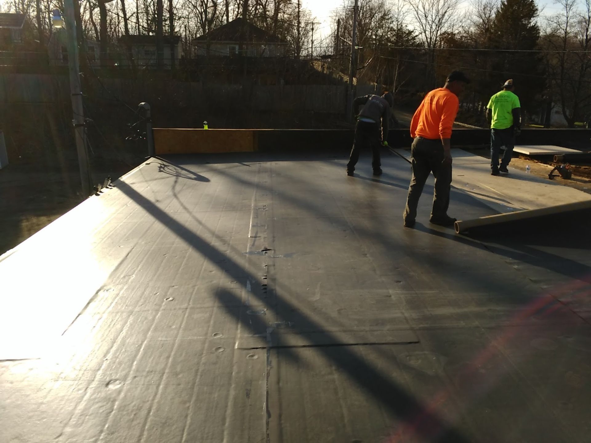 People setting up a skate park ramp outdoors in bright sunlight.