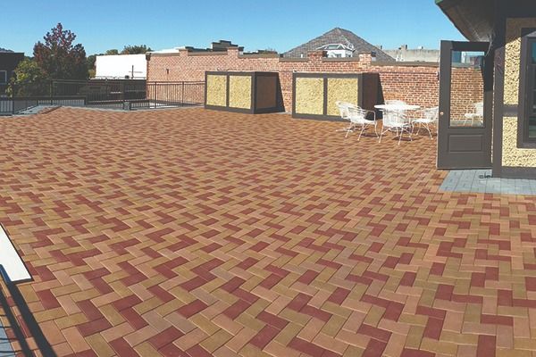 Brick-paved outdoor courtyard with brick buildings, tables, and chairs under a clear sky