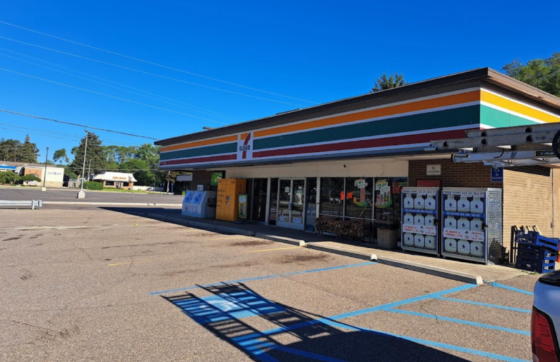 7-Eleven convenience store exterior on a sunny day, with striped green, orange, and red awning.