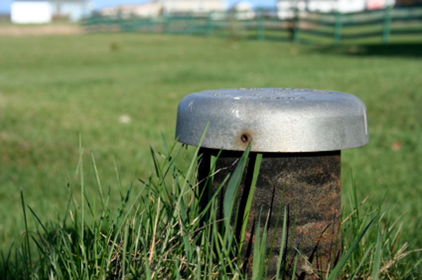 A metal pipe is sitting in the grass in a field.