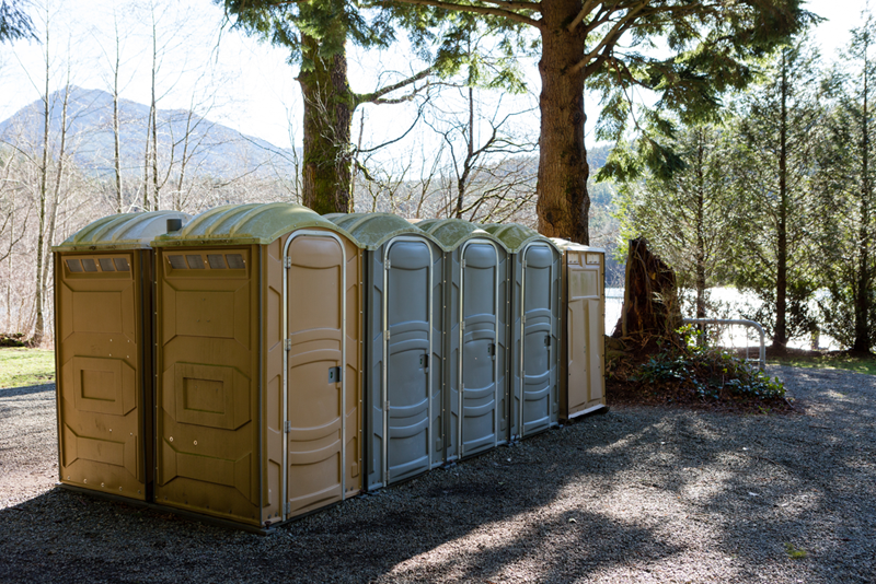 A row of portable toilets are lined up in a parking lot.