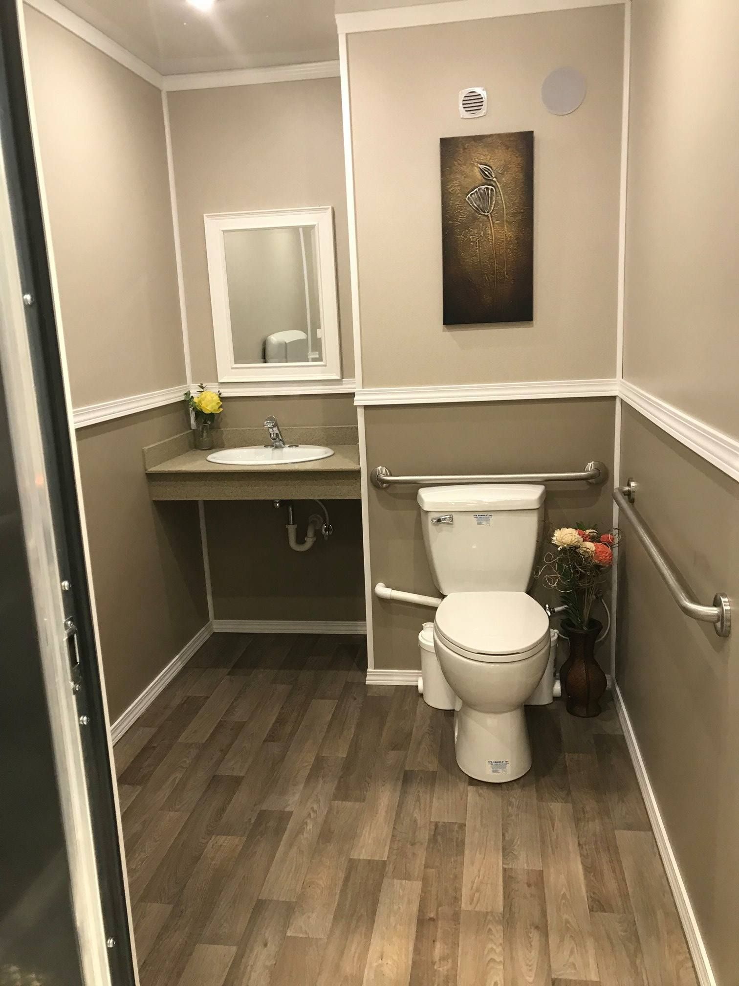 A bathroom with a toilet , sink and mirror.