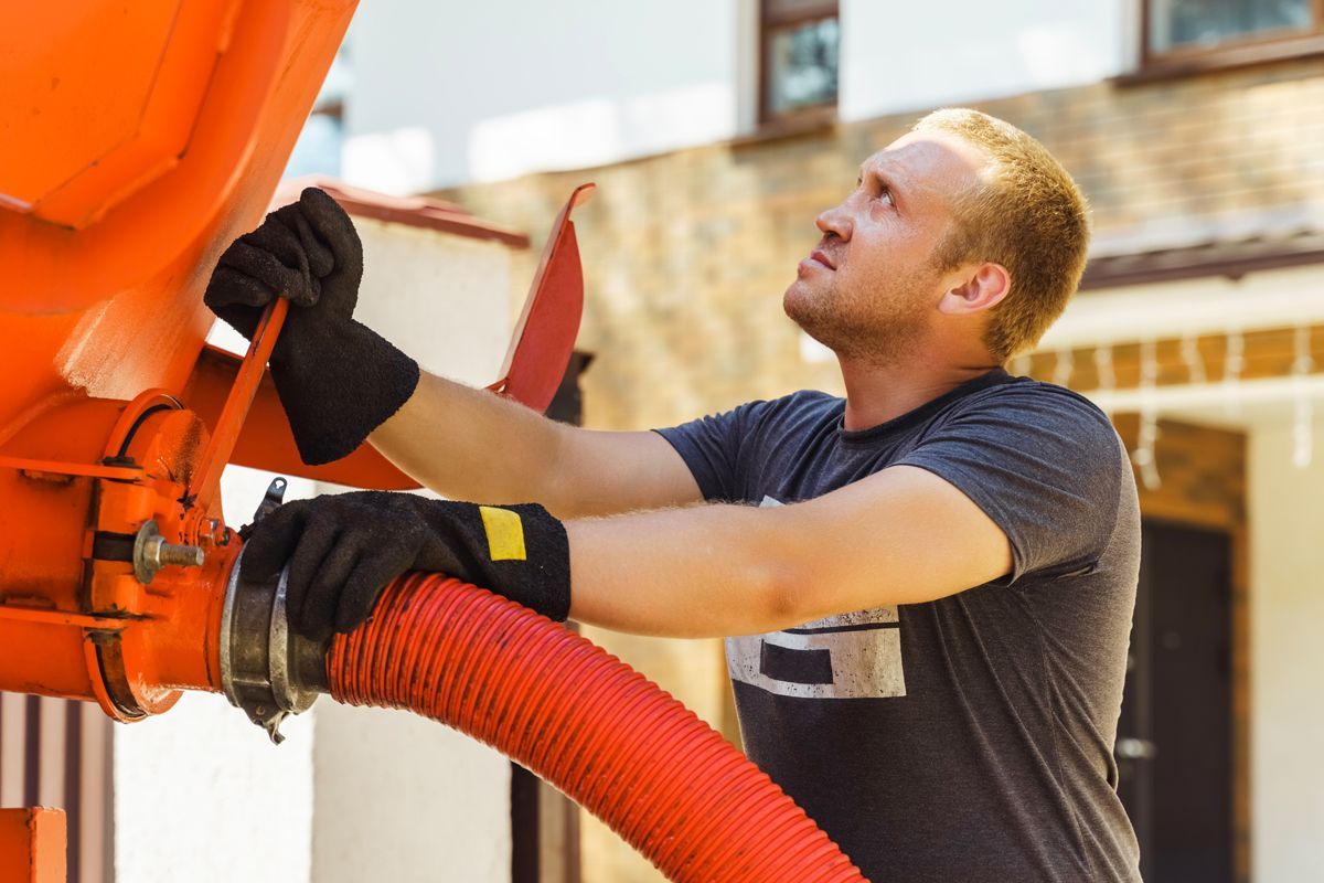 A man is working on a machine with a red hose.